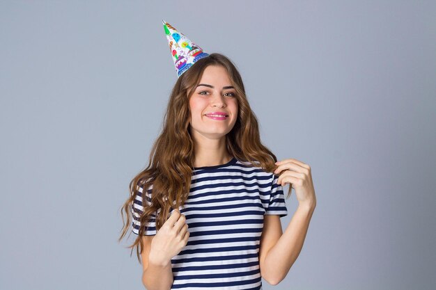 Young happy woman in stripped Tshirt and celebration cap making moustache of her long hair