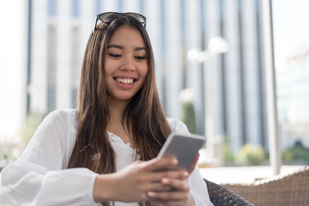 若い幸せな女性talikngと彼女の携帯電話でテキストメッセージ