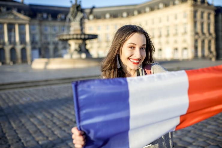 Photo フランスのボルドー市でフランスの旗を保持している若くて幸せな女性の観光客