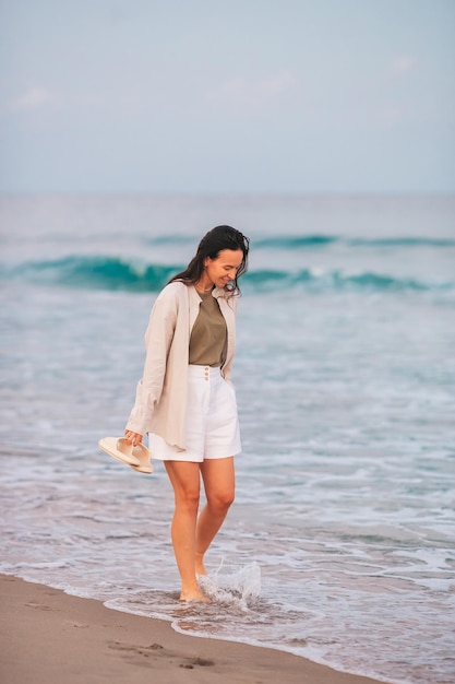 Giovane donna felice che cammina sulla spiaggia