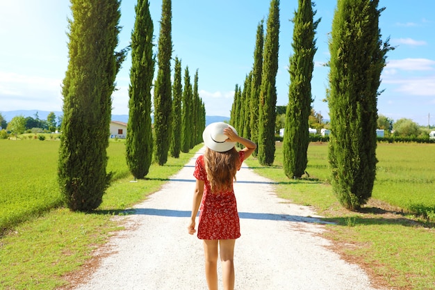 Young happy woman walking on pathway with typical Tuscany landscape