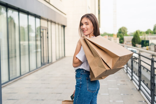 young happy woman walking with shopping bags outdoors on the street