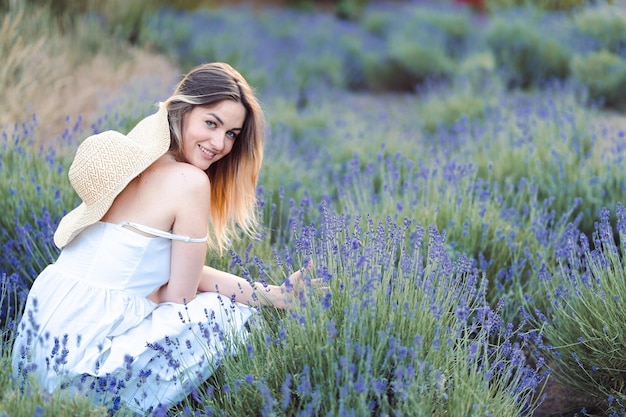 Foto giovane donna felice in prendisole bianco si siede tra lavanda lilla fresca harvest lavanda