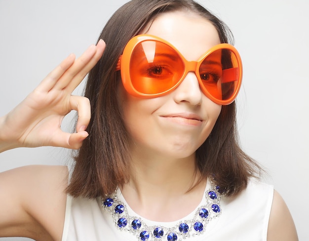 Молодая счастливая женщина с большими оранжевыми солнцезащитными очками, готовая к вечеринке