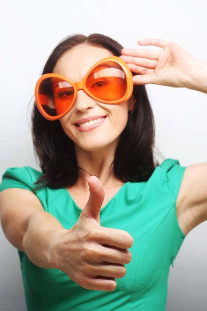 Молодая счастливая женщина с большими оранжевыми солнцезащитными очками