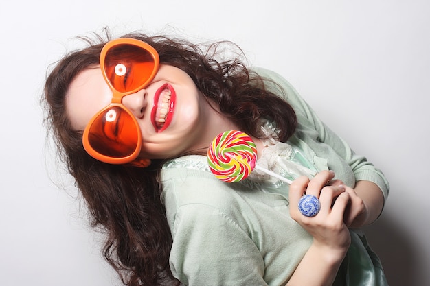 Giovane donna felice con grandi occhiali da sole arancioni