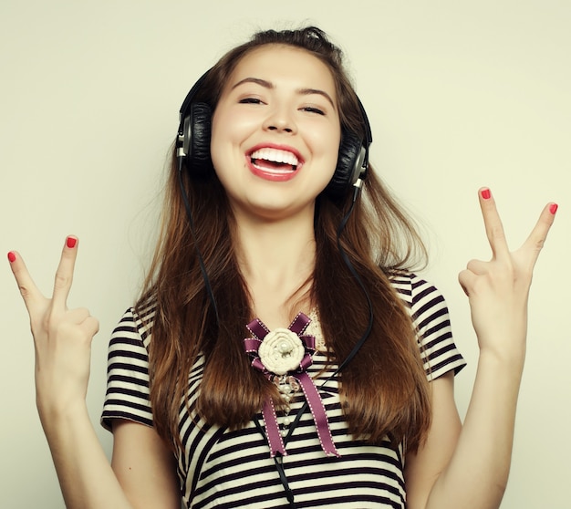 Young happy woman with headphones listening music over grey background