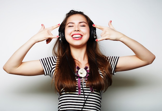 Young happy woman with headphones listening music over grey background