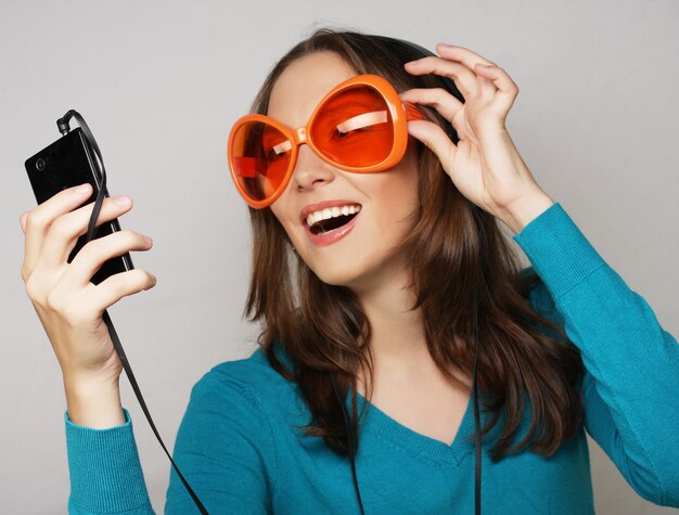 Giovane donna felice con le cuffie che ascolta musica su sfondo bianco