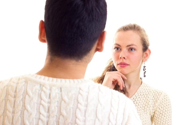 Young happy woman with long chestnut ponytail and young handsome man in white sweaters talking