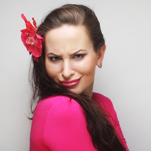 Young happy woman with pink flower in the hair