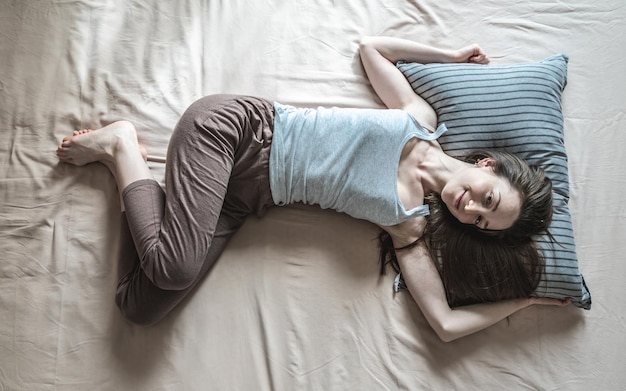 Young happy woman woke up in the morning and is lying in bed with enjoyment Concept of healthy sleep comfort and a pleasant start to a new day Top view