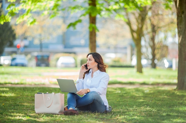 Young happy woman works at a laptop in nature