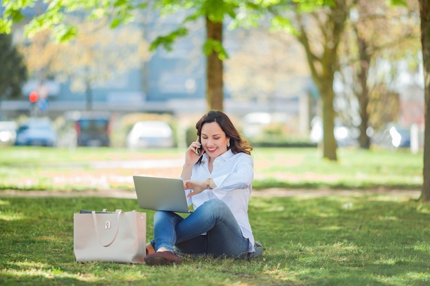 Young happy woman works at a laptop in nature