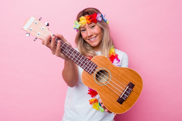 Giovane donna hawaiana che suona un ukulele isolato su sfondo rosa