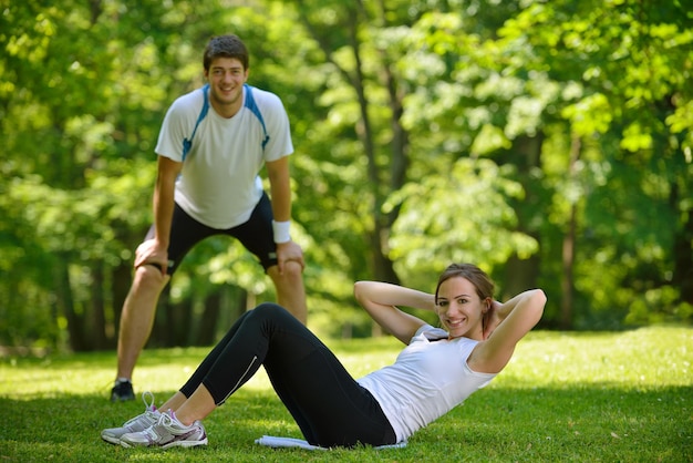 ジョギングや公園でのランニングの後、リラックスしてウォームアップするストレッチ運動をしている若い健康カップル