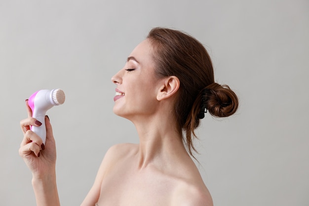 Young, healthy, beautiful, fresh skinned caucasian woman on a grey wall