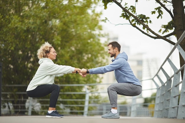 Young healthy couple holding hands and exercising during training in the park