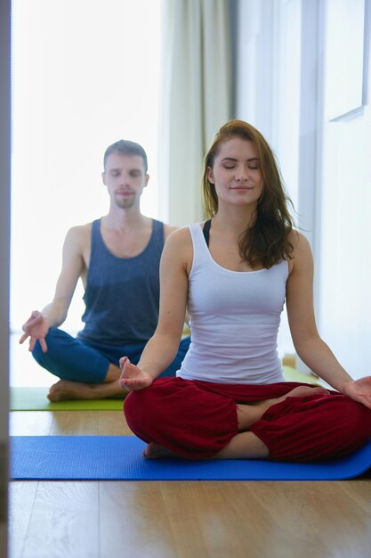 Young healthy couple in yoga position on white background