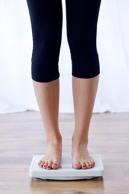 Young healthy girl on weight scales at home.