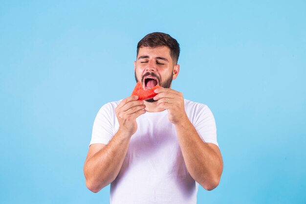 Young healthy handsome boy eating watermelon