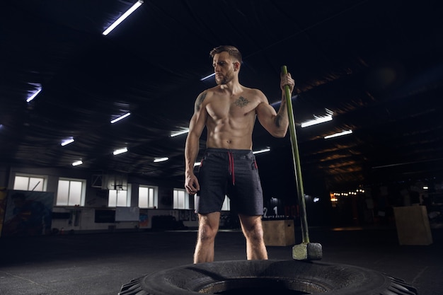 Young healthy male athlete doing exercises in the gym