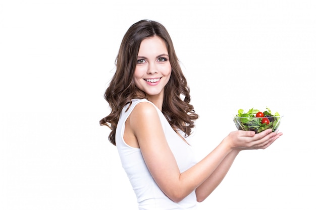 Young healthy woman holding vegetable salad on white.