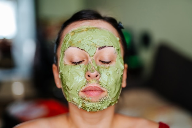 Young healthy woman making treatments and face clay mask.