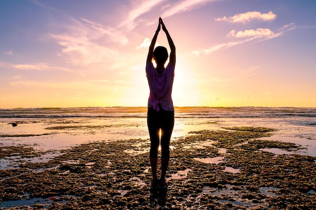 Young healthy woman practicing yoga on the beach at sunset strong confidence woman under the sunset