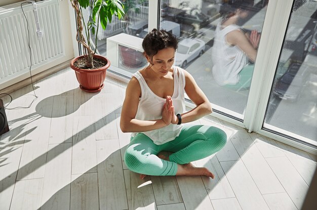 Giovane donna in buona salute a praticare yoga a casa