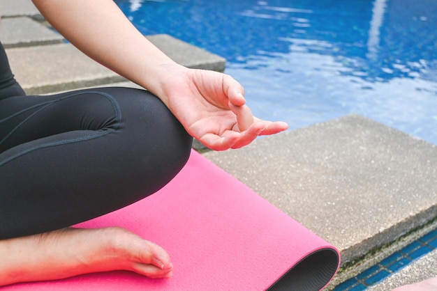 Young healthy woman in sportive top and leggings practicing yoga at home sitting in lotus pose