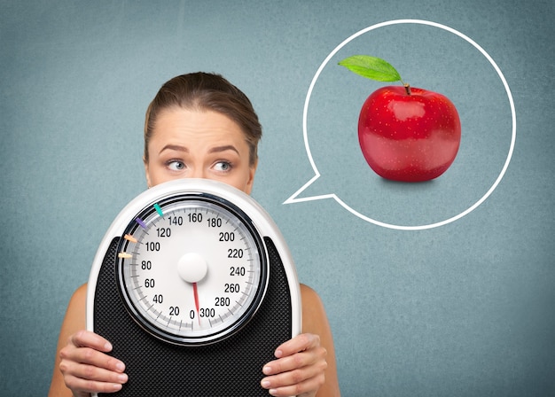 Young healthy woman with apple and scales isolated