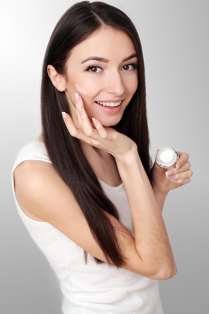 A young healthy woman with cosmetic cream on a clean fresh face