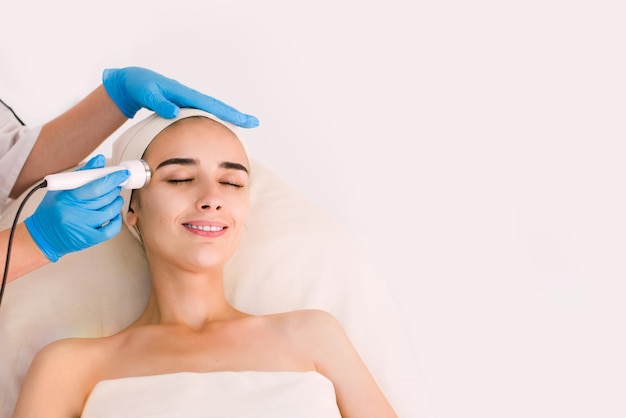 Young healthy woman with good skin doing cosmetic procedures in spa clinic. Isolated woman on white background.