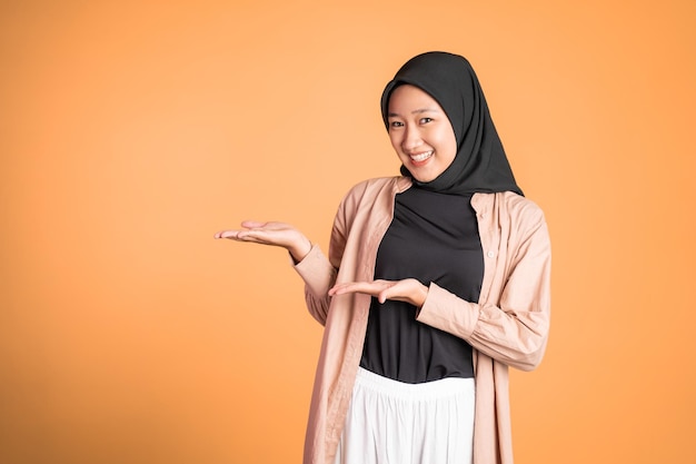 Young hijab woman with hand gesture presenting something