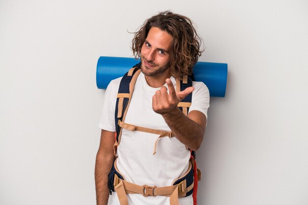 Young hiker caucasian man isolated on gray background pointing with finger at you as if inviting come closer.