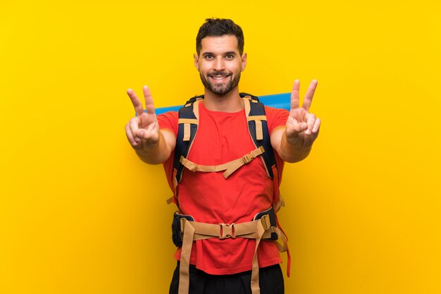 Foto giovane uomo della viandante che sorride e che mostra il segno di vittoria