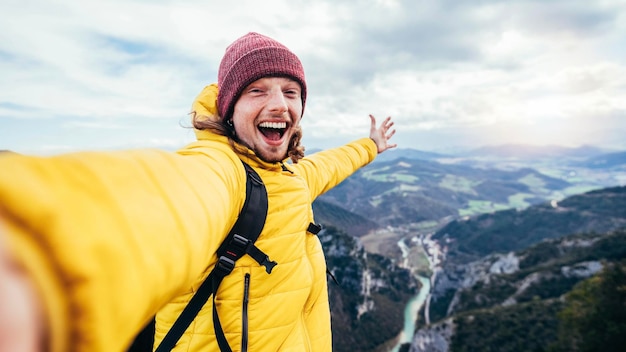 Young hiker man taking selfie portrait on the top of mountain