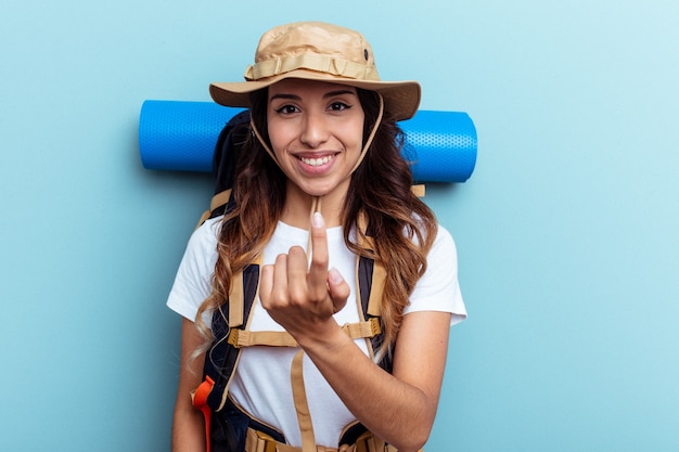 Foto giovane escursionista donna di razza mista isolata su sfondo blu che punta con il dito su di te come se invitasse ad avvicinarsi.