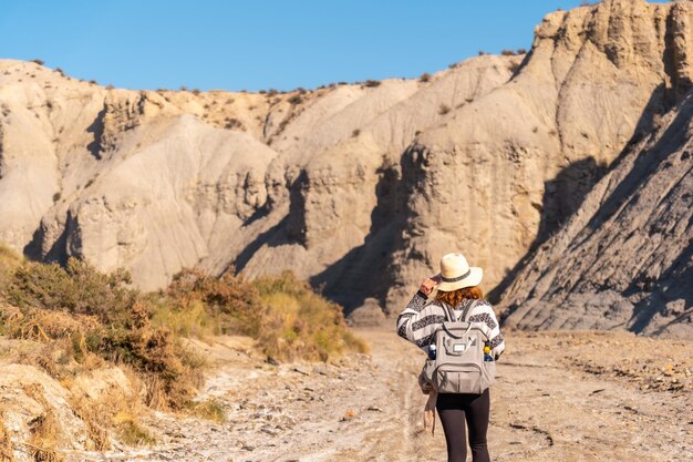 A young hiker with backpack and straw hat in the desert of Tabernas, AlmerÃÂÃÂ­a province, Andalusia. On a trek in the Rambla del Infierno