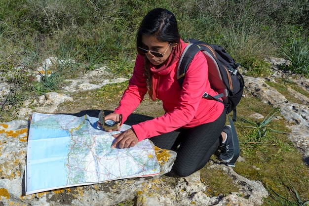 Foto giovani escursionisti seduti a terra a guardare una vecchia mappa con una coppia di escursioniste a bussola in natura