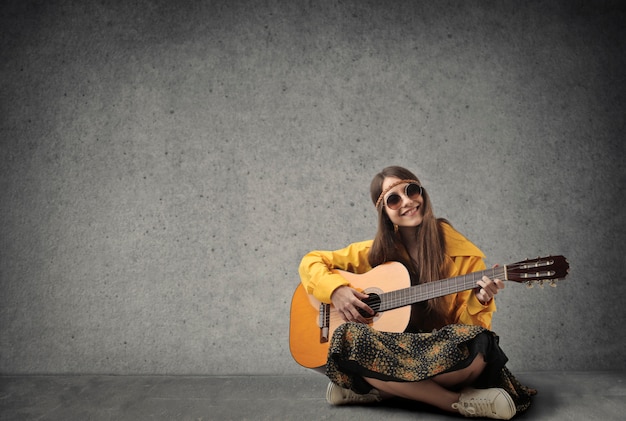 Young hippie girl playing on a guitar