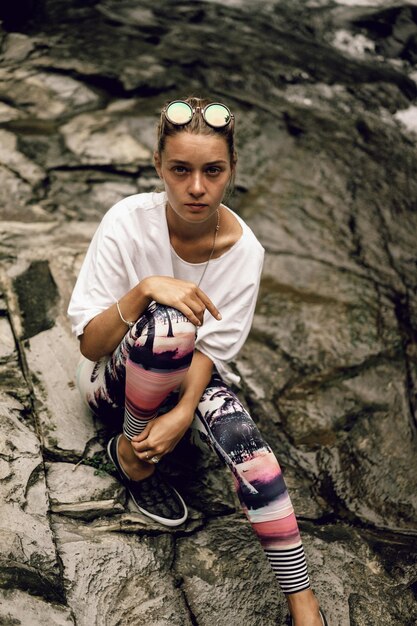 young hippie woman in bright leggings and round glasses in nature