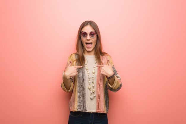 Young hippie woman on pink background surprised, feels successful and prosperous