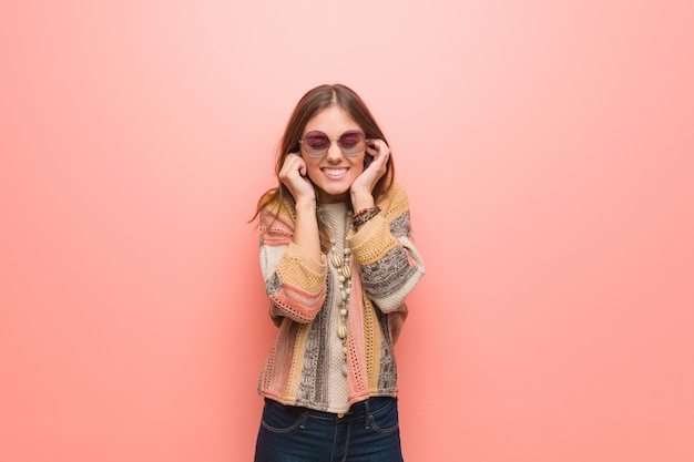 Young hippie woman on pink covering ears with hands