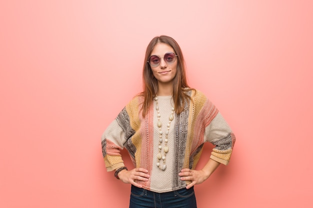 Young hippie woman on pink  with hands on hips