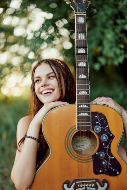 Young hippie woman with eco image smiling and looking into the camera with guitar in hand in nature on a trip