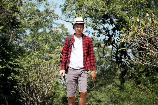 Young hipster Asian man traveling with a backpack in summer forest trip travel lifestyle concept