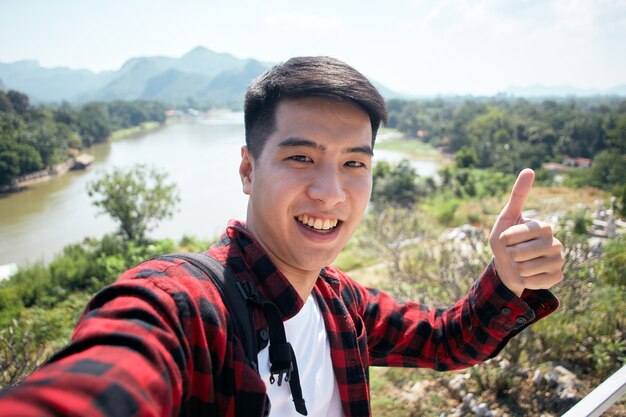 Young hipster Asian man traveling with a backpack in summer forest trip travel lifestyle concept