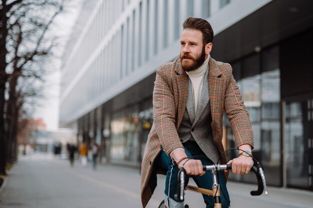 高品質の写真で自転車で仕事に行く若いヒップスターのビジネスマン